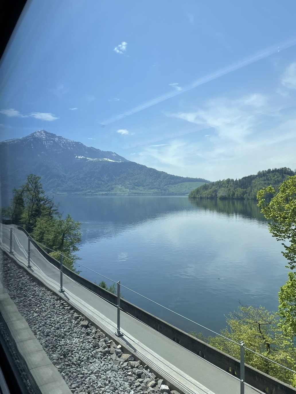 Un lago con una montagna sullo sfondo, il tutto visto attraverso il finestrino di un treno.