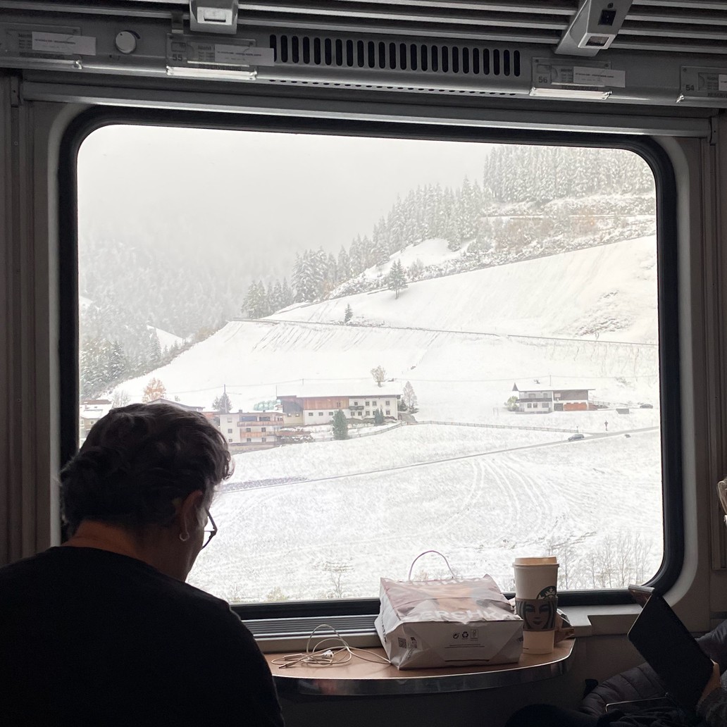 interno di un treno con una finestra che dà su un paesaggio montagnoso ricoperto di neve.